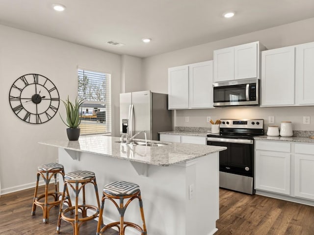 kitchen with white cabinets, appliances with stainless steel finishes, and a kitchen island with sink