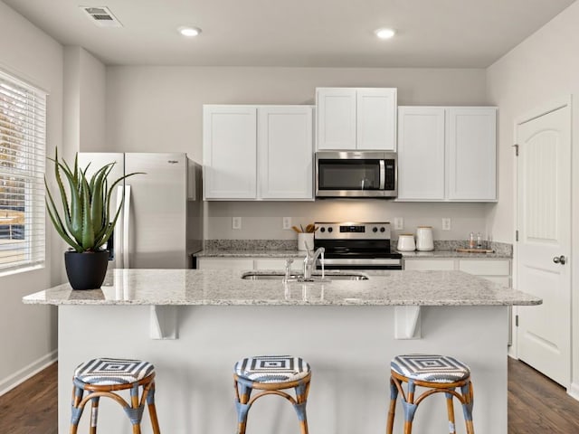 kitchen with appliances with stainless steel finishes, sink, an island with sink, and white cabinetry