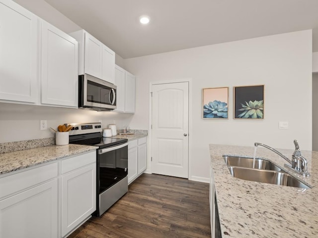 kitchen with sink, white cabinetry, stainless steel appliances, dark hardwood / wood-style flooring, and light stone countertops