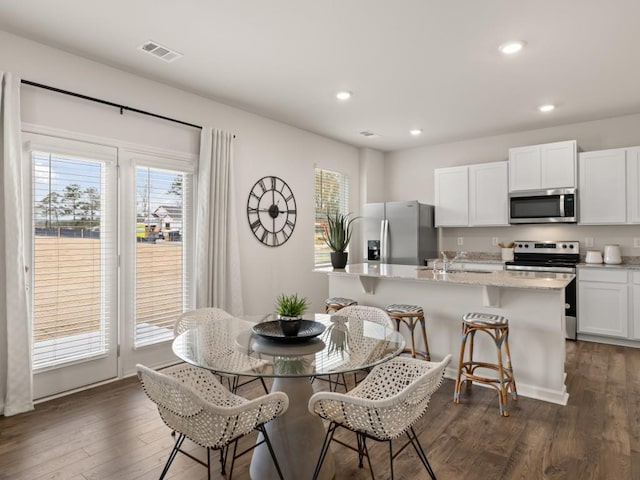 dining space with sink, dark wood-type flooring, and a healthy amount of sunlight