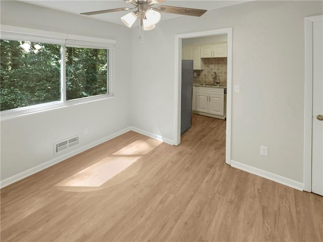 empty room featuring light hardwood / wood-style flooring, ceiling fan, and sink