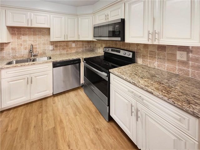 kitchen featuring sink, light hardwood / wood-style flooring, decorative backsplash, appliances with stainless steel finishes, and light stone counters