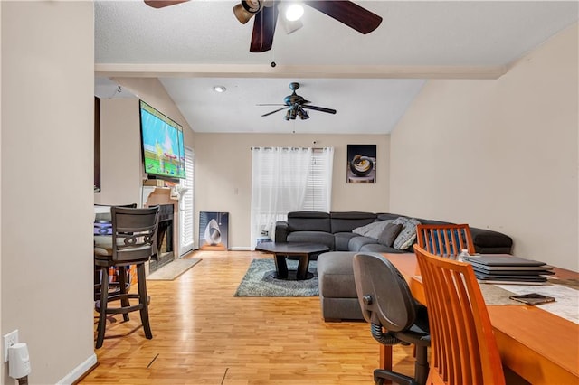 living room featuring ceiling fan, vaulted ceiling with beams, and light hardwood / wood-style floors