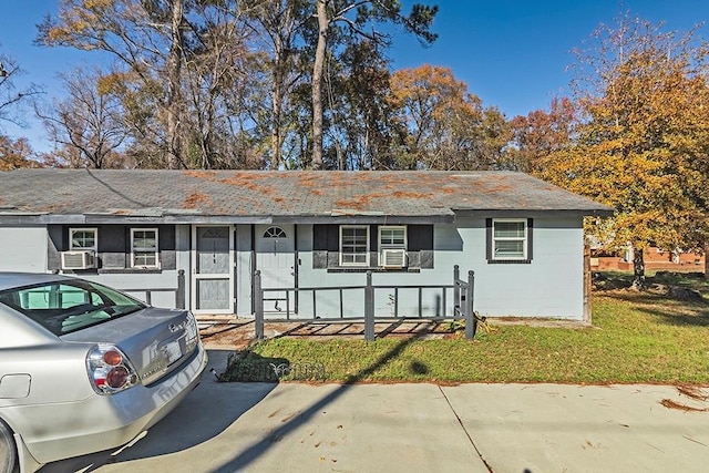 ranch-style home featuring a front yard, a porch, and cooling unit