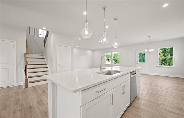 kitchen featuring decorative light fixtures, sink, white cabinets, and a kitchen island with sink