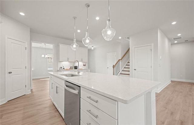 kitchen featuring dishwasher, sink, hanging light fixtures, a kitchen island with sink, and white cabinets