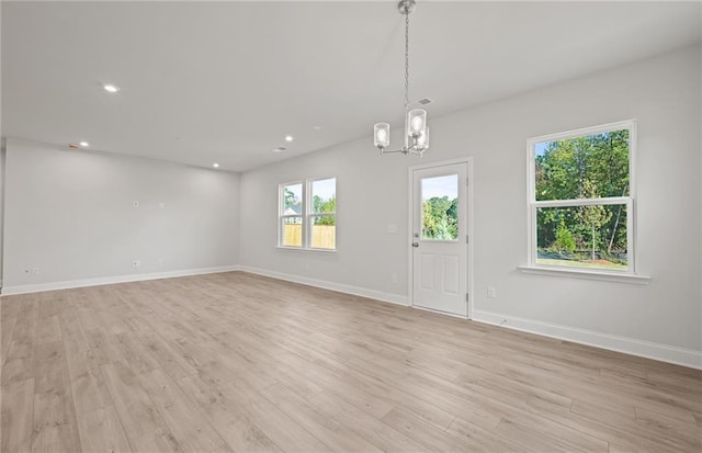 spare room featuring light hardwood / wood-style floors and an inviting chandelier