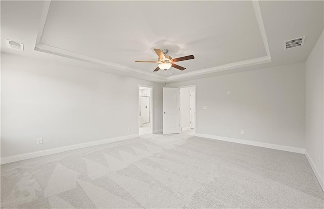 carpeted empty room with ceiling fan and a tray ceiling