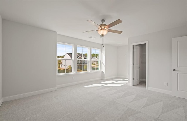 unfurnished bedroom featuring ceiling fan, a walk in closet, light carpet, and a closet