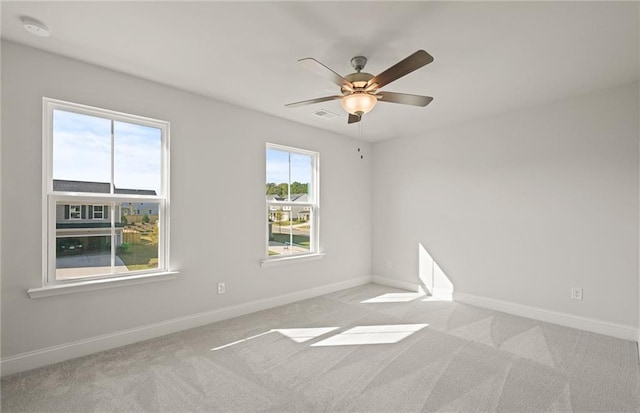 carpeted empty room featuring ceiling fan and plenty of natural light