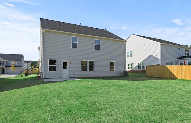 back of property with central AC and a lawn