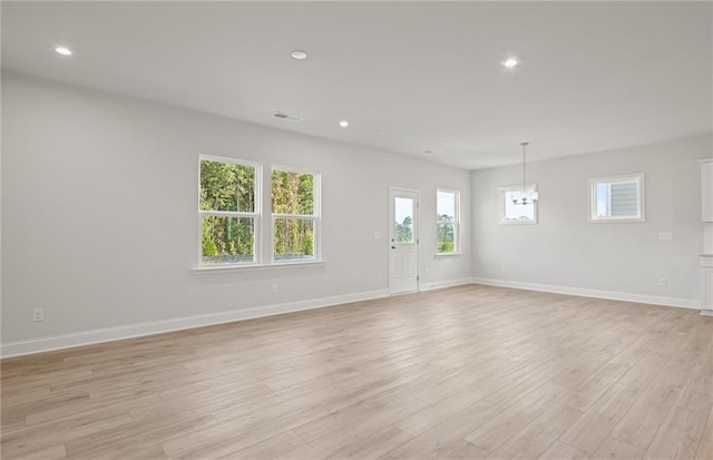 empty room featuring light wood-type flooring and an inviting chandelier