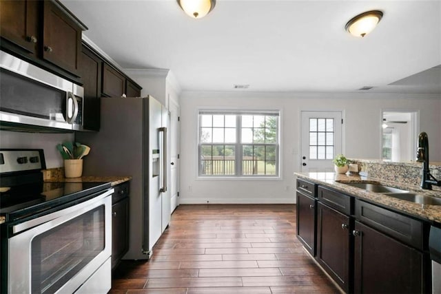 kitchen featuring dark brown cabinets, sink, light stone countertops, appliances with stainless steel finishes, and dark hardwood / wood-style flooring