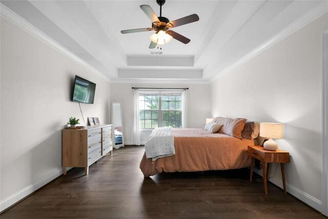 bedroom featuring dark wood-type flooring, ceiling fan, crown molding, and a tray ceiling