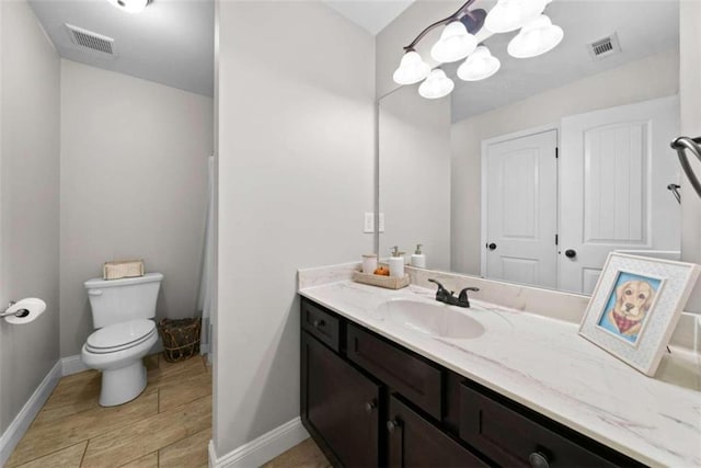 bathroom with toilet, vanity, and wood-type flooring