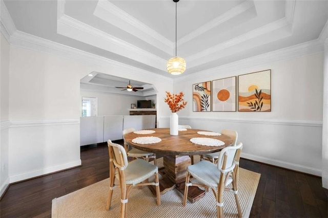 dining space with ceiling fan, a raised ceiling, and dark hardwood / wood-style flooring