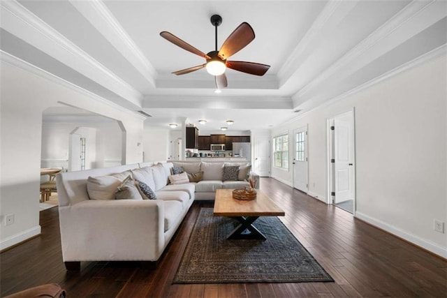 living room with crown molding, ceiling fan, a raised ceiling, and dark hardwood / wood-style flooring