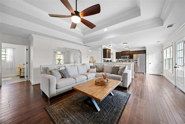 living room with ornamental molding, ceiling fan, a tray ceiling, and dark hardwood / wood-style flooring