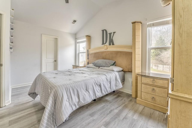 bedroom with multiple windows, lofted ceiling, and light hardwood / wood-style floors