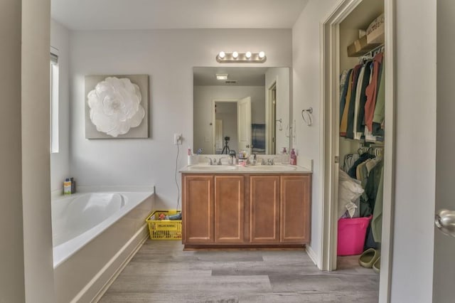 bathroom with hardwood / wood-style flooring, vanity, and a washtub