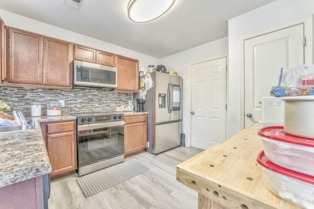 kitchen featuring backsplash, stainless steel appliances, sink, and light wood-type flooring