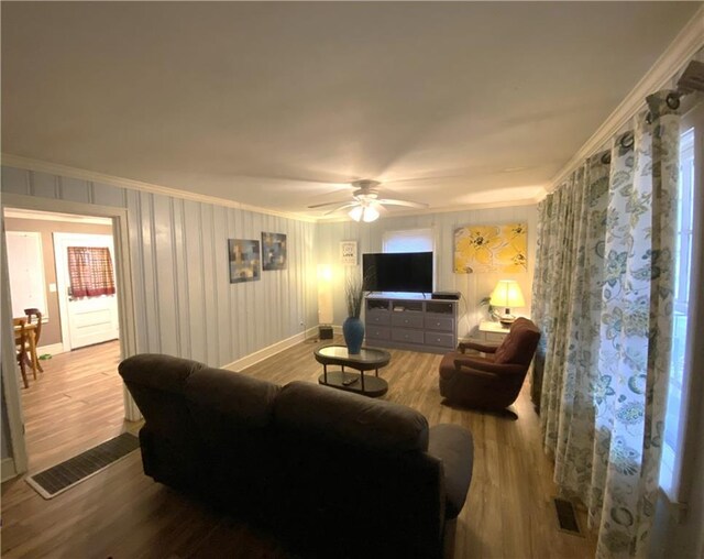 living room featuring crown molding, ceiling fan, and light hardwood / wood-style flooring