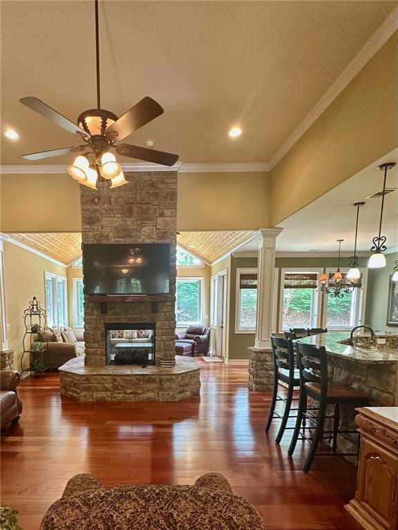 3397 Holly Glen Dr, Dacula, GA 30019 - living area with dark wood-style floors, a ceiling fan, a stone fireplace, ornate columns, and ornamental molding
