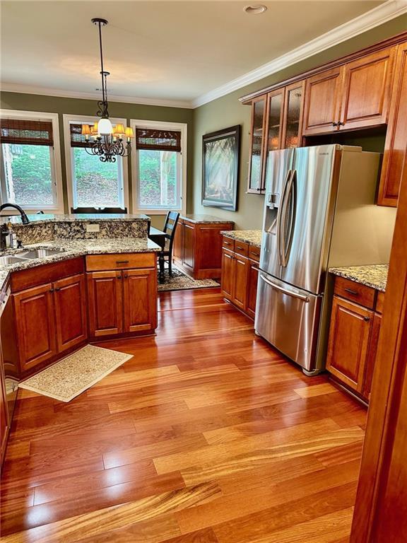 3397 Holly Glen Dr, Dacula, GA 30019 - kitchen featuring a sink, brown cabinetry, crown molding, decorative light fixtures, and stainless steel fridge with ice dispenser