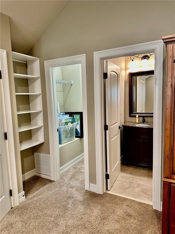 3397 Holly Glen Dr, Dacula, GA 30019 - hallway with visible vents, lofted ceiling, light colored carpet, and a sink