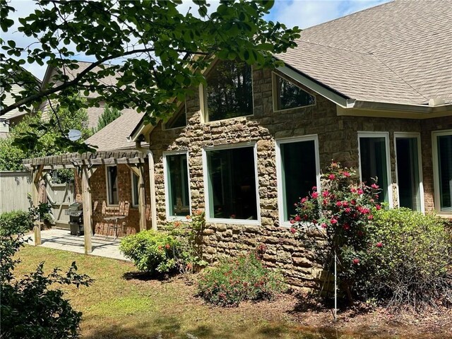3397 Holly Glen Dr, Dacula, GA 30019 - view of front of house with a pergola, a shingled roof, a patio area, stone siding, and fence