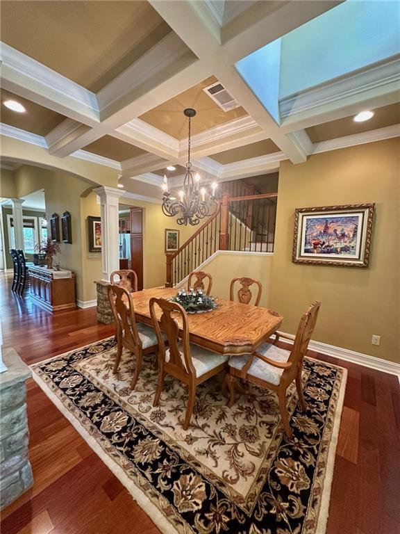 3397 Holly Glen Dr, Dacula, GA 30019 - dining space with arched walkways, wood finished floors, coffered ceiling, baseboards, and ornate columns