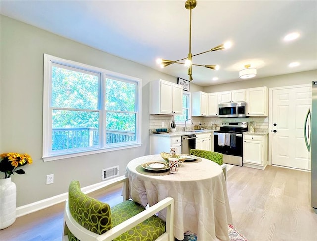 430 Thornbush Trce, Lawrenceville, GA 30046 - kitchen with appliances with stainless steel finishes, light wood finished floors, tasteful backsplash, white cabinets, and a chandelier