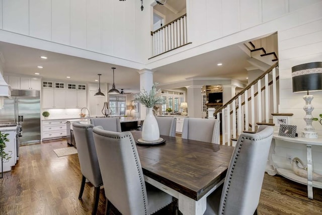 dining room with a towering ceiling, ornate columns, and dark wood-type flooring