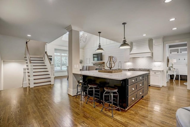 kitchen featuring white cabinetry, pendant lighting, custom range hood, and wood-type flooring