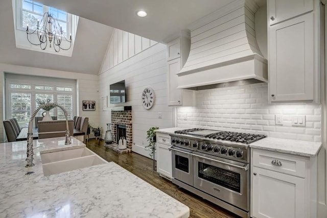 kitchen featuring white cabinets, custom exhaust hood, dark wood-type flooring, double oven range, and a fireplace