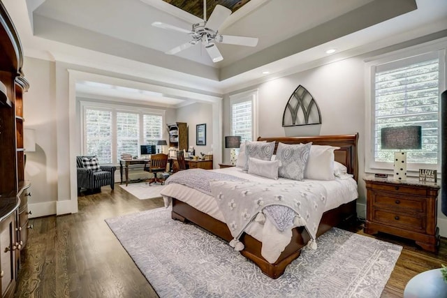 bedroom with ceiling fan, dark hardwood / wood-style flooring, and a tray ceiling