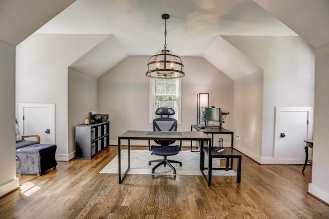 office space with a chandelier, wood-type flooring, and vaulted ceiling