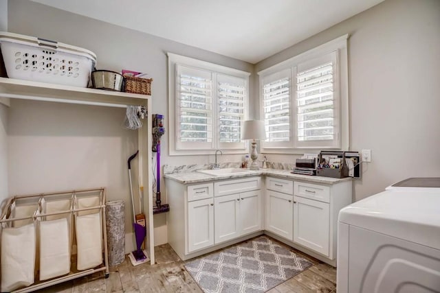 clothes washing area with cabinets, sink, light hardwood / wood-style floors, and independent washer and dryer