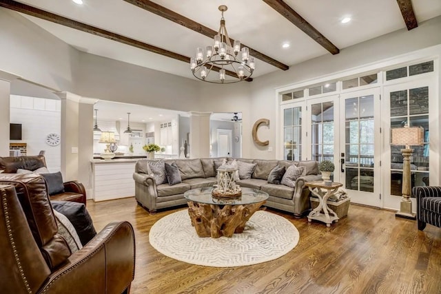 living room with beamed ceiling, an inviting chandelier, hardwood / wood-style flooring, and french doors