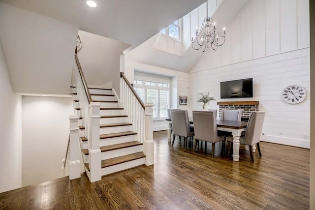 dining space featuring dark hardwood / wood-style flooring, an inviting chandelier, and high vaulted ceiling