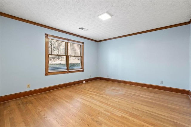 unfurnished room with light wood finished floors, baseboards, visible vents, ornamental molding, and a textured ceiling