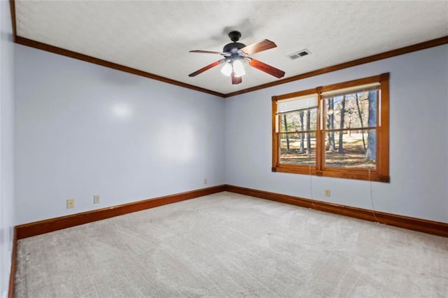 empty room featuring baseboards, carpet floors, visible vents, and crown molding