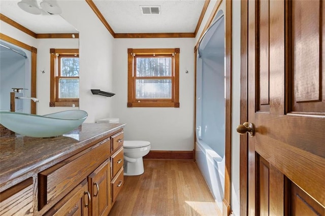 full bath with toilet, wood finished floors, visible vents, baseboards, and crown molding