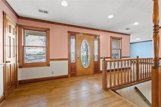 entrance foyer with ornamental molding, baseboards, visible vents, and light wood finished floors