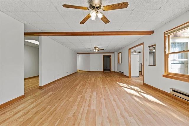 spare room with a baseboard radiator, baseboards, a drop ceiling, and light wood finished floors