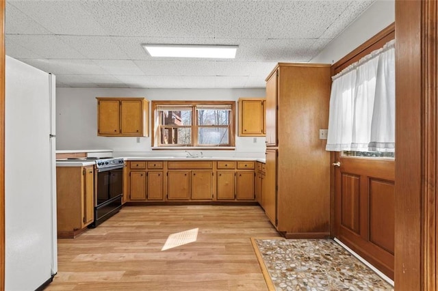 kitchen with brown cabinets, freestanding refrigerator, light countertops, and gas stove