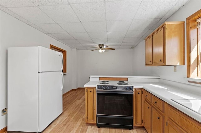 kitchen with light wood-style flooring, a peninsula, electric range, light countertops, and freestanding refrigerator