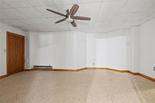 spare room with a ceiling fan, a baseboard radiator, baseboards, and a drop ceiling