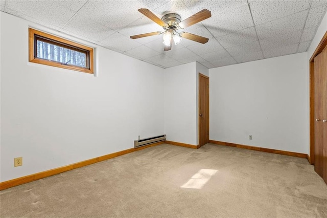 interior space featuring baseboards, light colored carpet, ceiling fan, a paneled ceiling, and a baseboard heating unit