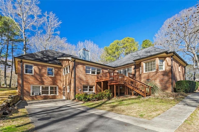 back of house featuring a wooden deck, a chimney, stairway, and brick siding